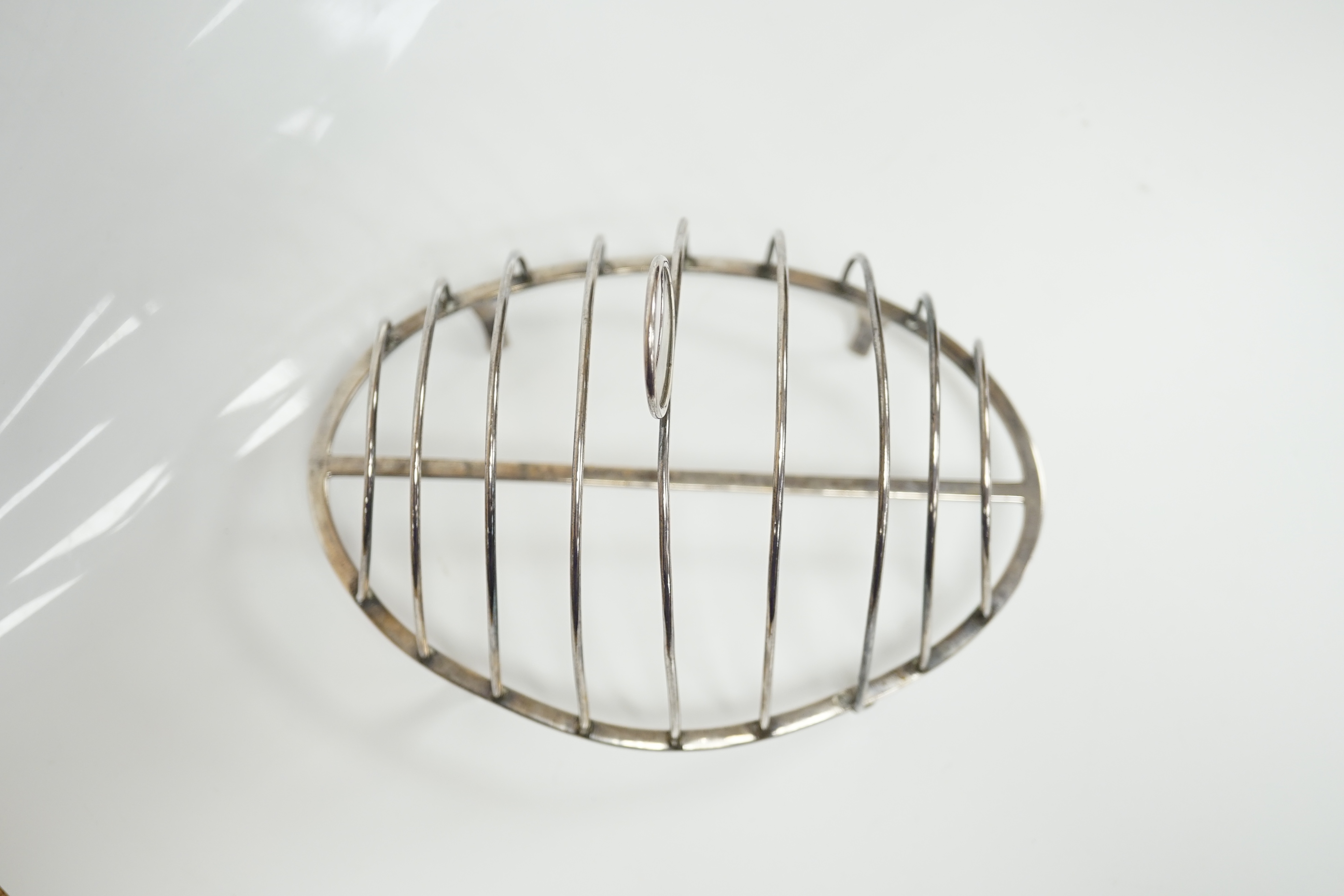 A George III silver oval nine bar toast rack by Robert & Samuel Hennell, with crescent ring handle, on four tapering feet, London, 1803, length 18.4cm. Condition - poor to fair